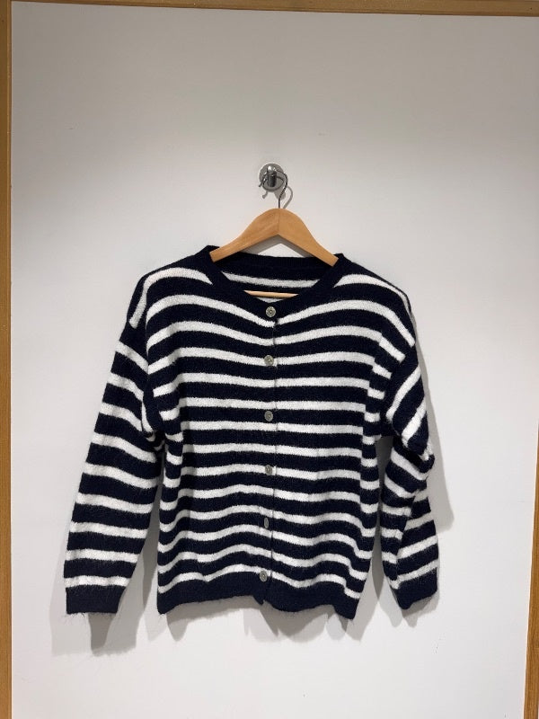 Gilet rayé bleu marine et crème en maille douce italienne suspendu sur un cintre en bois
