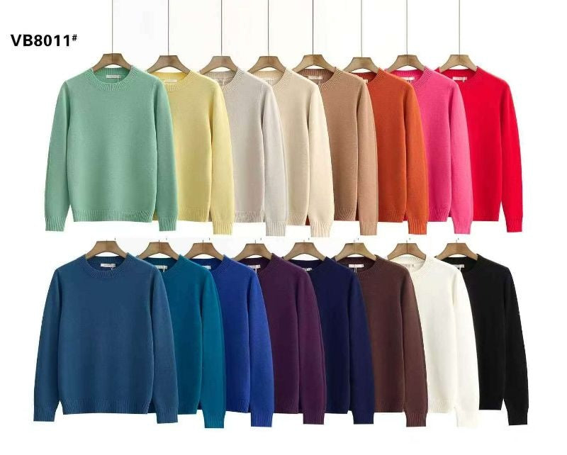 Présentation de la collection de pulls en maille douce dans 16 coloris variés, suspendus sur des cintres en bois sur fond blanc.